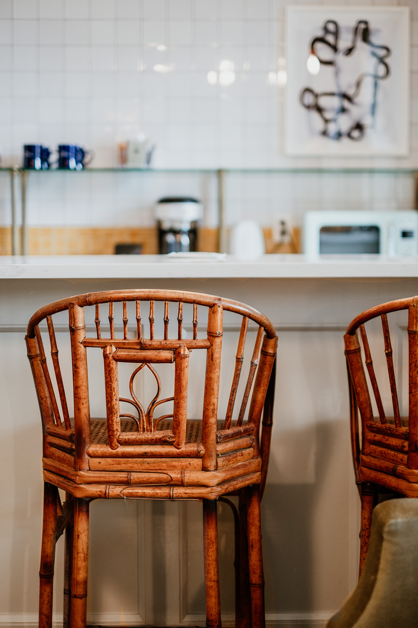 Two bamboo bar stools in a cozy café setting with a modern countertop and kitchen appliances in the background.