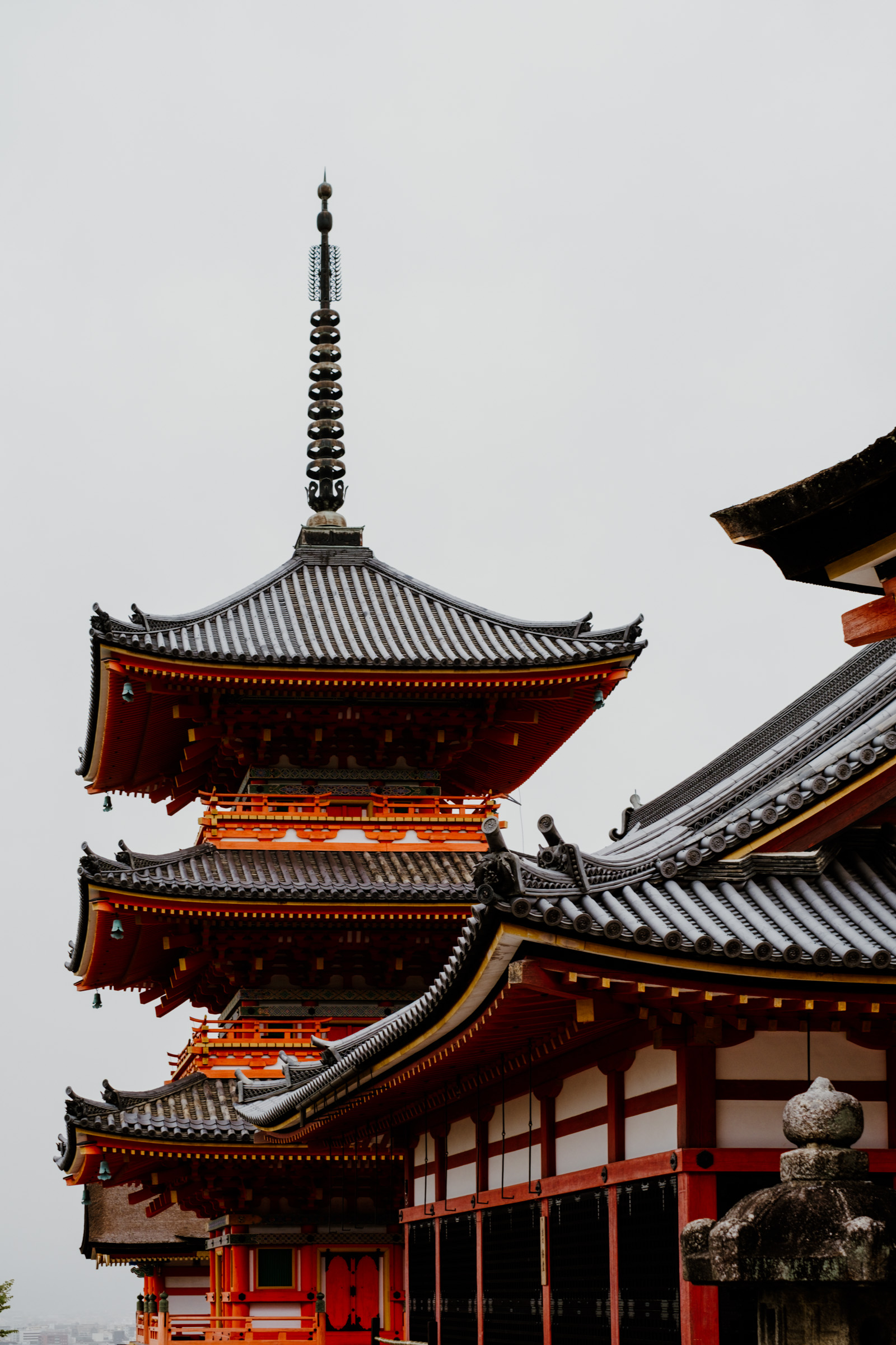 A traditional Japanese pagoda with intricate roof details and vibrant red accents, set against a gray sky.